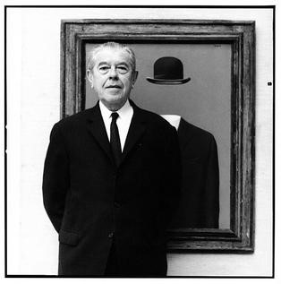 Photograph of Rene Magritte, in front of his painting The Pilgrim.